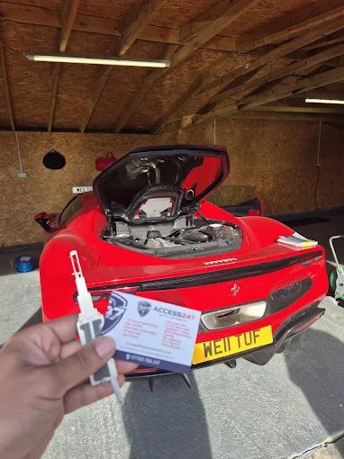 A freshly cut car key held in front of a red Ferrari
